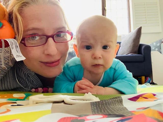 Mum and baby lying on tummy on play mat looking towards the camera