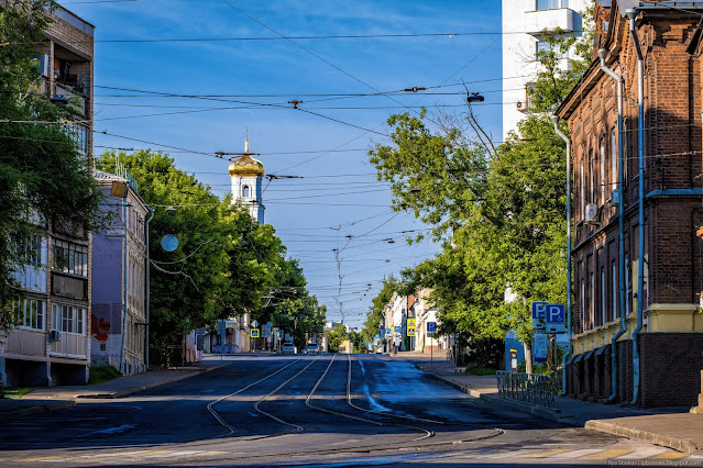 Городская улица с домами по бокам и церковью на фоне