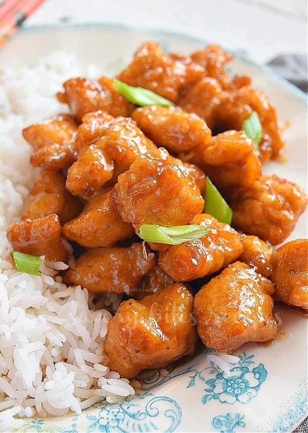 panda express orange chicken on a plate with rice topped with chopped spring onion