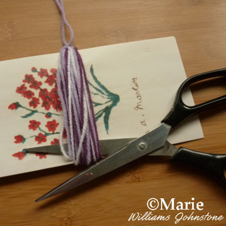 Using scissors to cut the yarn strands on the bottom of the tassel