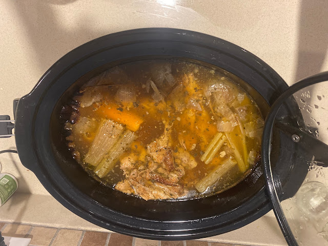 Crock pot with bones, herbs and vegetables simmering