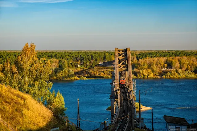 Электричка едет по железнодорожному мосту через реку