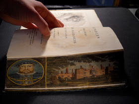 A bent fore edge, revealing Hampton Palace and a portrait of Henry VIII."