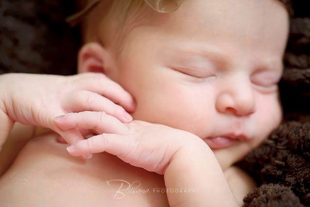 close-up of beautiful baby girl's crossed hands while lying on brown blanket