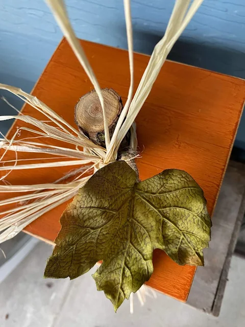 Photo of a tree branch pumpkin stem with silk leaf and raffia