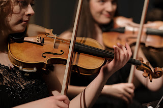 photo of female violin players in an orchestra.