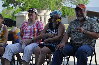 His mom and dad sitting in the circle, she has a shower cap on and a pair of fake glasses with a banana nose attached.