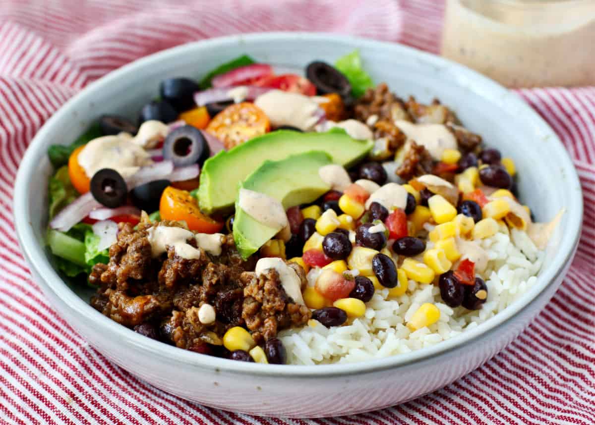 Burrito Bowls with Corn and Tomatoes with Chipotle Ranch on top.