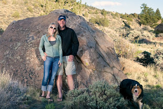 a couple poses by rocks with their dog