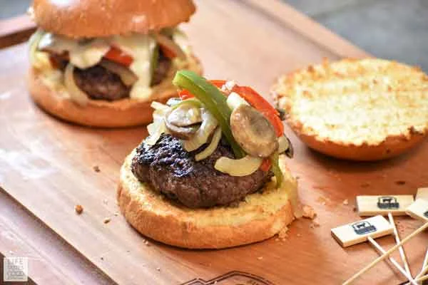 Assembling Philly Cheese Steak Burgers with vegetables on top