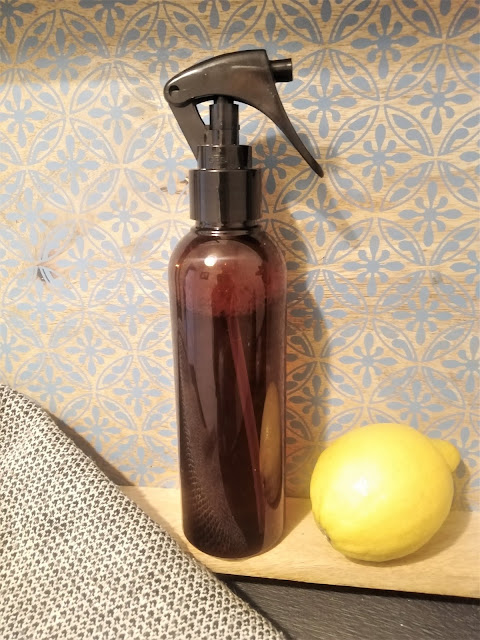 brown glass cleaning spray bottle, wooden tray and a lemon