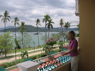 Nan on the balcony at Country Inn with Panama Canal and Balboa Yacht Club behind her