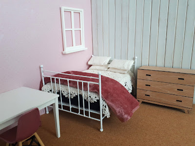 One-twelfth scale modern miniature bedroom with bed, dresser, table and chair. The floor is cork.