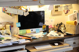 A very cluttered desk with the keyboard pulled out underneath it.