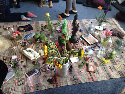 Altar made up of things attendees' sacred things like photos, jewelry, flowers, etc. 