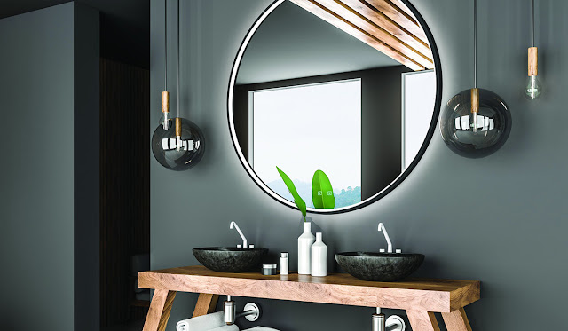 Modern bathroom with wood vanity and vessel sinks with round mirror.