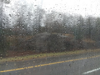 Rain drops on the window with a blurred vision of the road at the side.