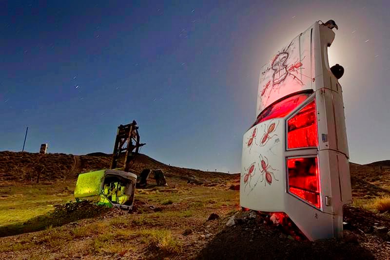 At the edge of Goldfield, a small town in the middle of Nevada, multiple cars, buses, vans, and limos are buried vertically in the desert as if they are growing out of the ground.