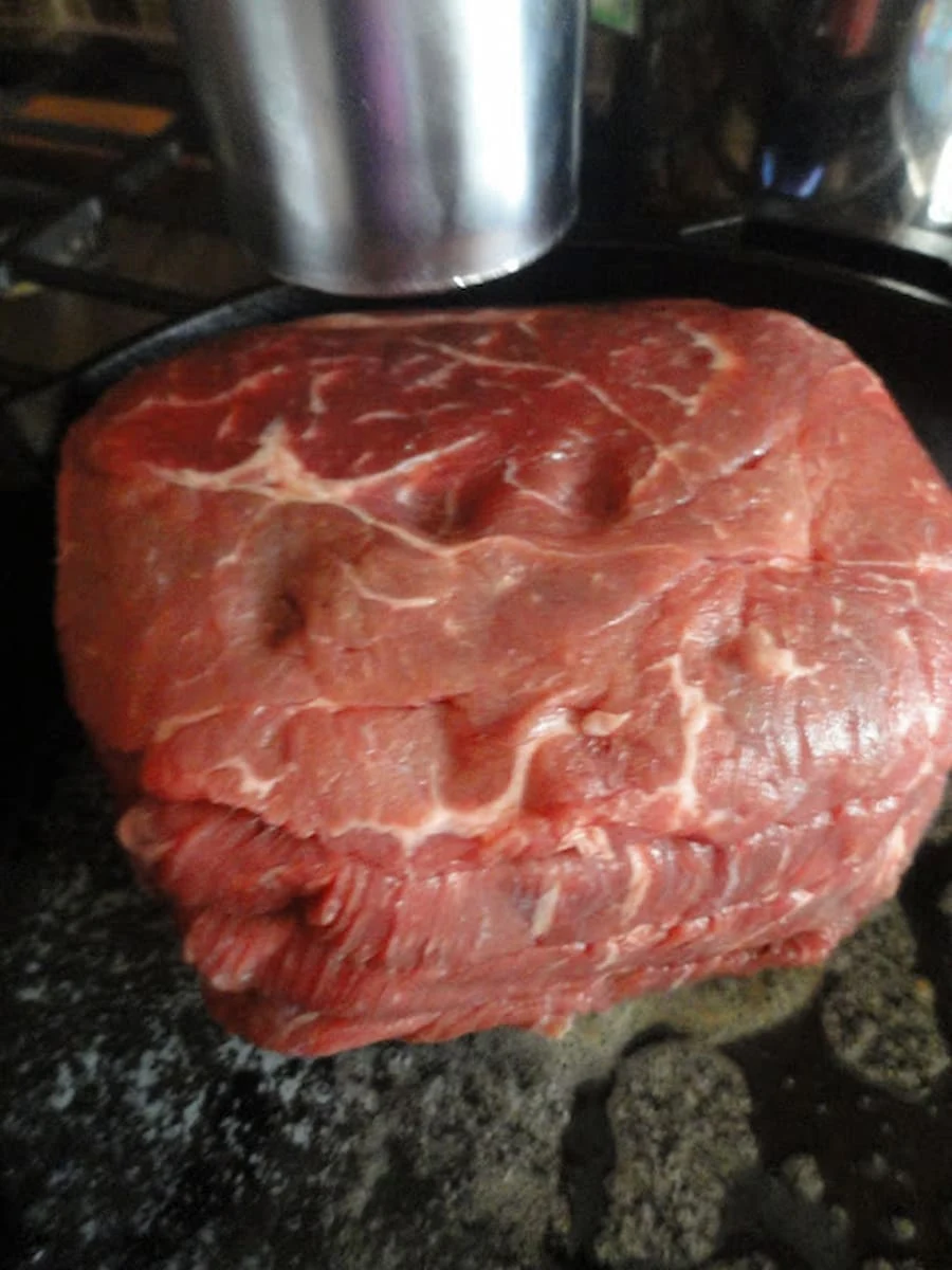 A Beef Chuck Roast being browned in a cast iron pan.