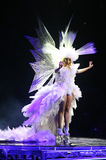 Lady Gaga wearing a white gown with a headdress and wings