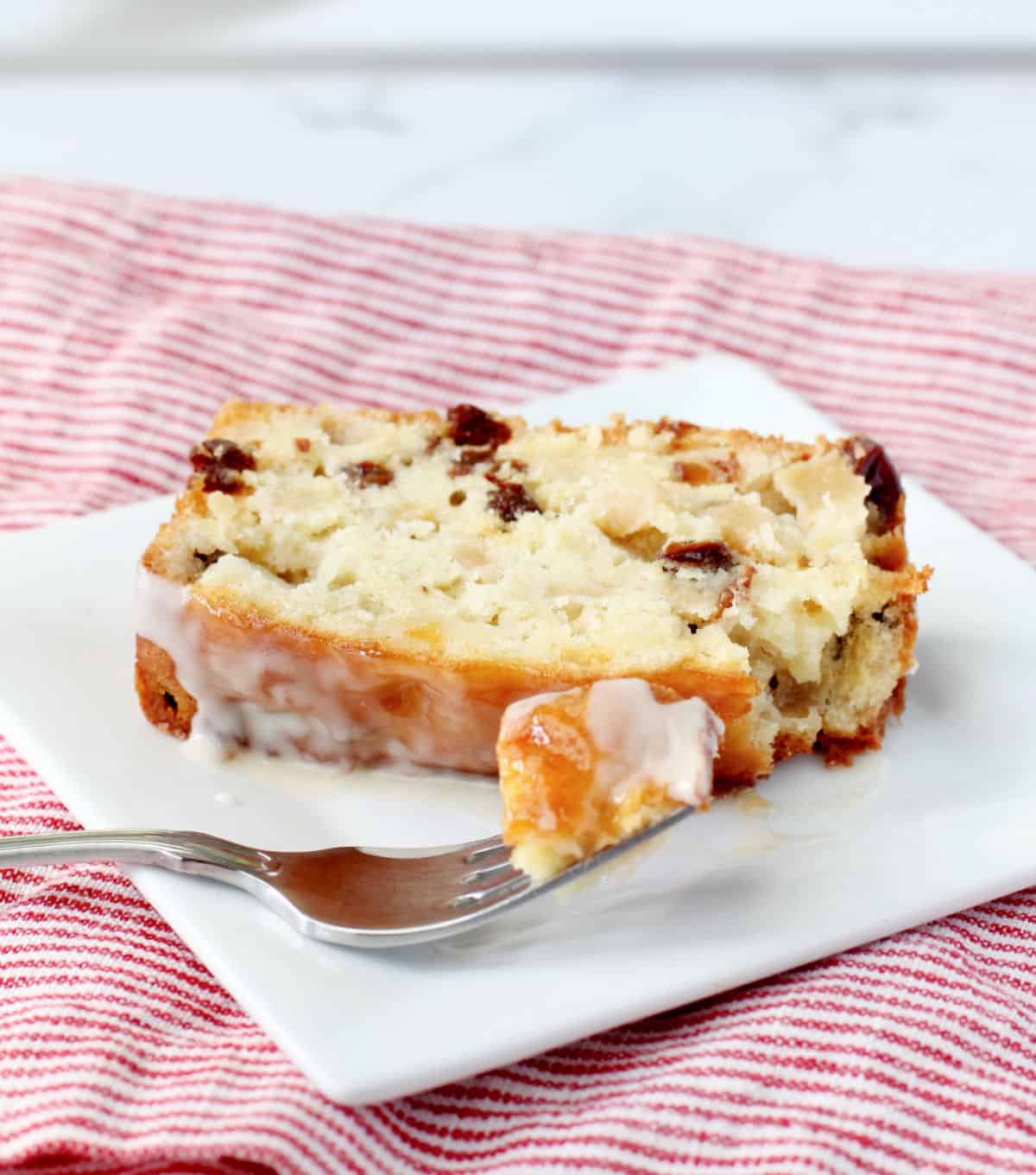 Classic French Apple Cake slice with a bite on a fork on a white plate.