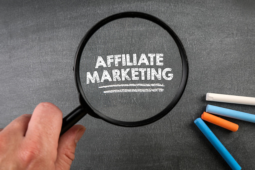 hand holding magnifying glass with the words "affiliate marketing " magnified