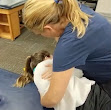 Dr. Lew adjusting the patient's midback in the hug yourself position on her back.