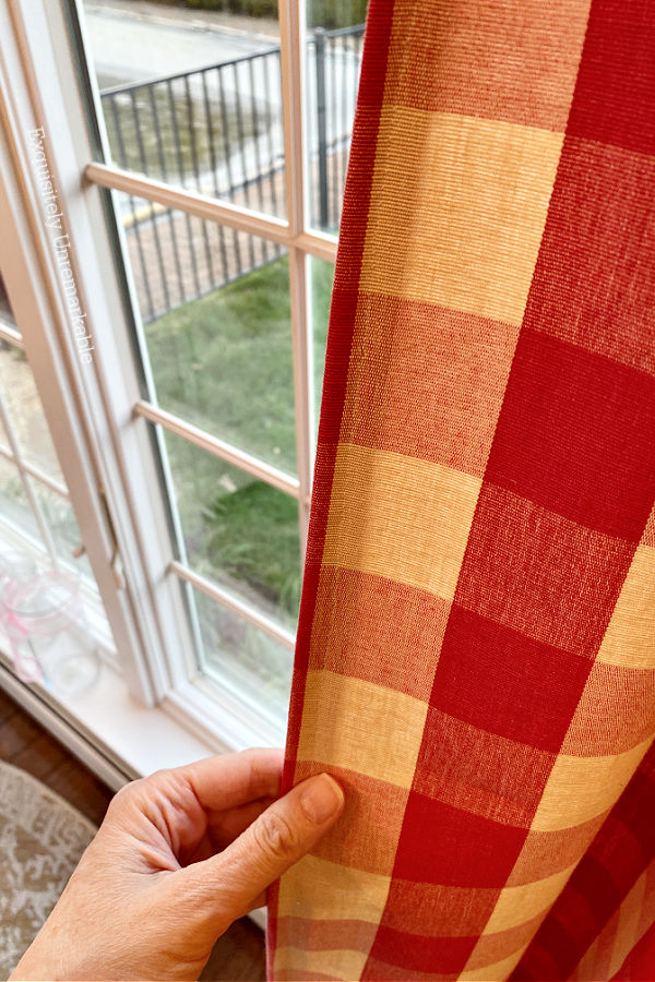 A hand grabbing curtain panel edge to show where trim is added