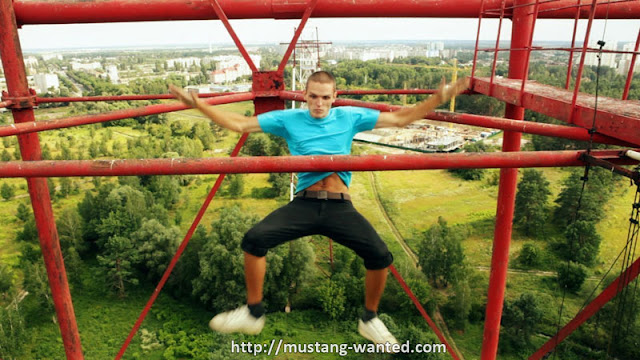 Man hanging from the tall steel object 