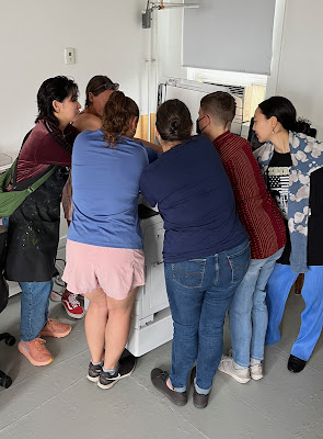 A photo of a group of people putting their hands on a copy machine to scan their hands together.
