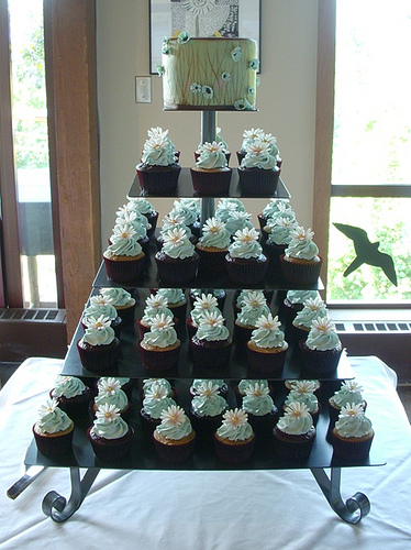 Square shaped cupcake tower set over four lovely tiers with a mini cake to 