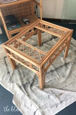 Rattan end table on painter's drop cloth with glass top removed.