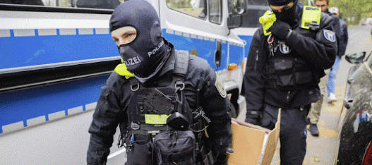 des policiers qui emportent un carton lors d’un raid à Berlin