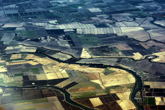 An aerial look at a river, and plots of land below.