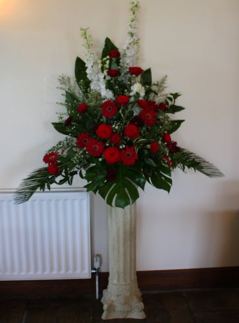 The Burgundy and White Pedestal design of Delphiniums Roses and Gerberas 