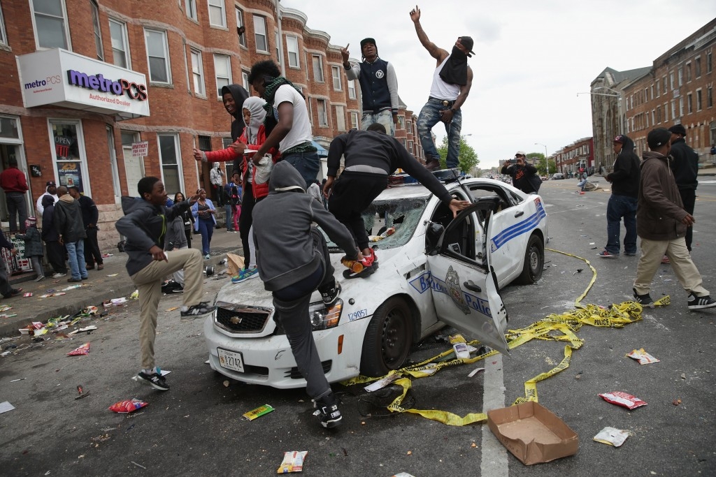 70 Of The Most Touching Photos Taken In 2015 - Demonstrators climb on a destroyed Baltimore Police car during violent protests following the funeral of Freddie Gray.