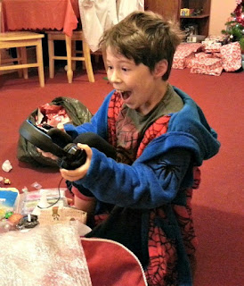 Boy with happy face, opening a Christmas present. 