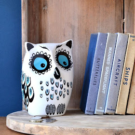 ceramic owl piggy bank, sitting on shelf next to some books