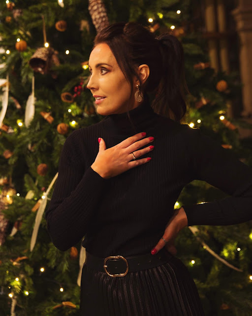 woman in black outfit in front of christmas tree