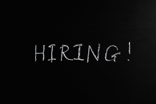 A black chalkboard with writing that reads, "HIRING!"