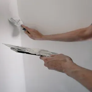 Foto imagem em fundo branco de um profissional pintando a parede de um imóvel alugado.