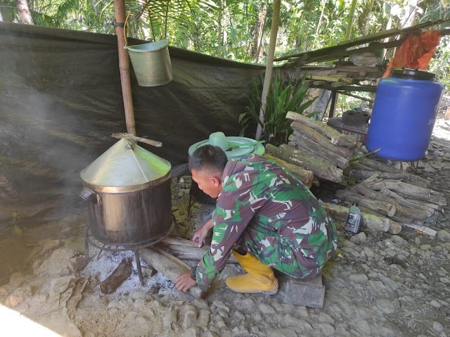 Anggota satgas TMMD memasak dengan cara tradisional menghilangkan kayu bakar