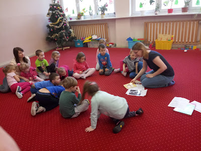 Na zdjęciu bibliotekarz pokazujący przedszkolakom portrety znanych bajkowych misiów