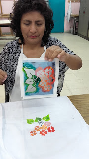 Retiro del stencil, se observa la figura de flores pintada en la remera blanca Escuela 37