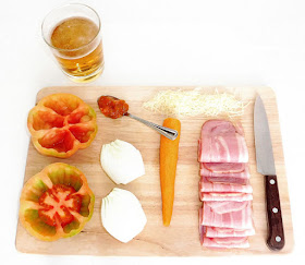 Ingredientes para realizar tomates rellenos de bacon a la cerveza sobre una tabla de madera