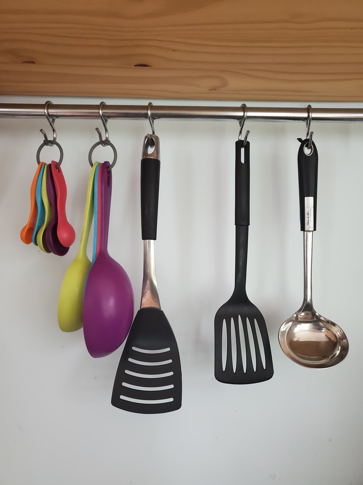 measuring spoons and kitchen tools hanging on metal bar