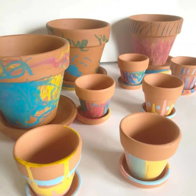 Terracotta flowerpots decorated with designs made by melting crayons onto them