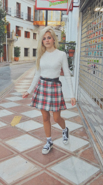 Estilo de los años 90 inspirado en Jennifer Aniston en Friends con suéter blanco, falda de tablas cuadros escoceses, zapatillas y calcetines blancos con raya negra