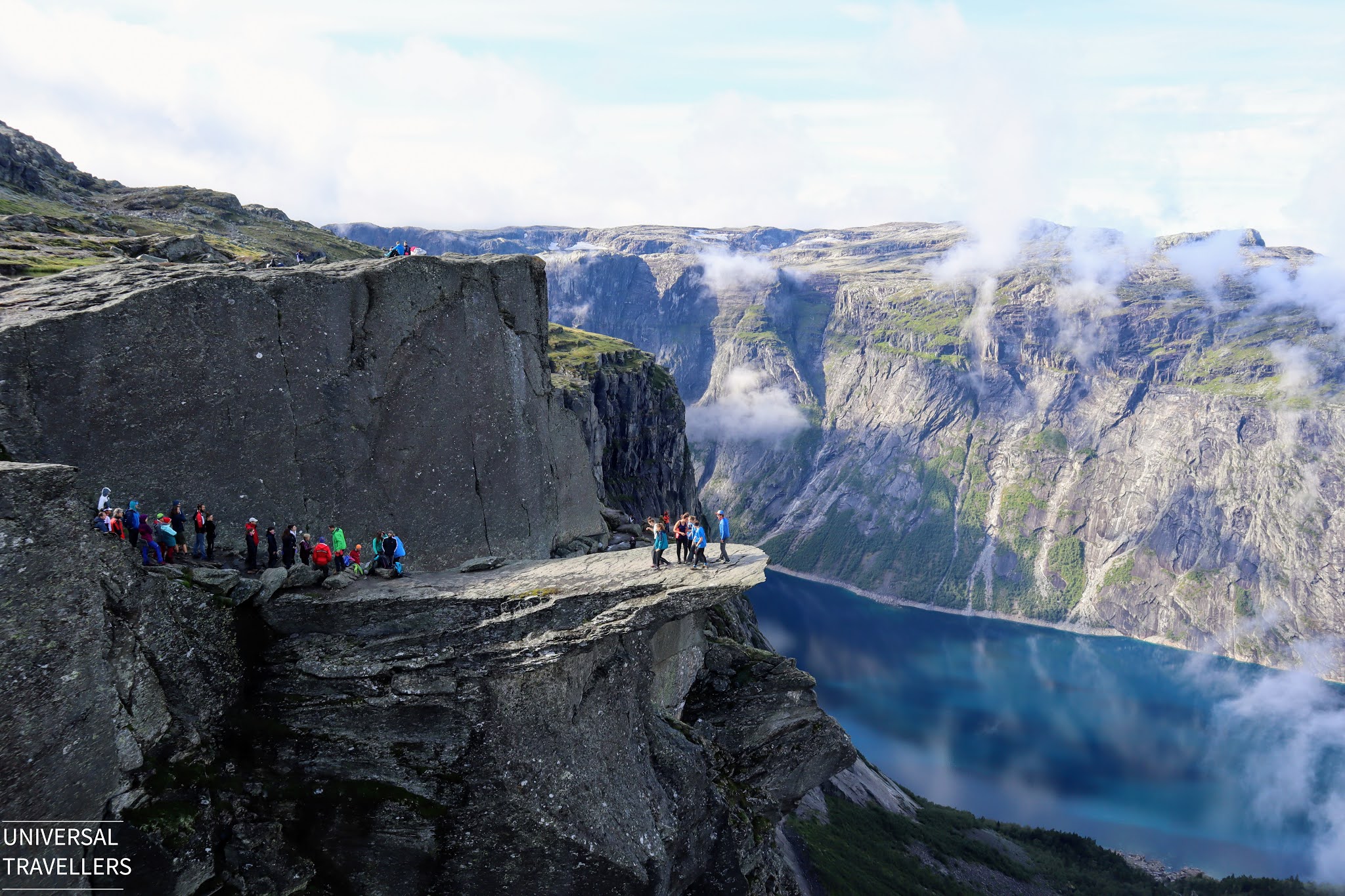 Hikers are waiting in the queue to reach the Trolltunga cliff while others hikers are posing for the pictures