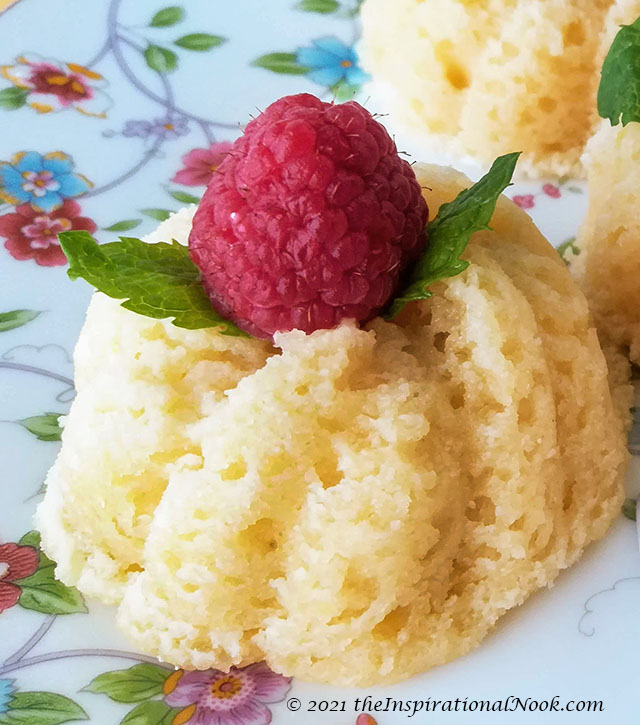 Small yellow bundt cakelet with a raspberry and mint leaves